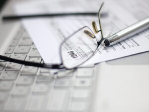 Glasses and pen on tax form and laptop.